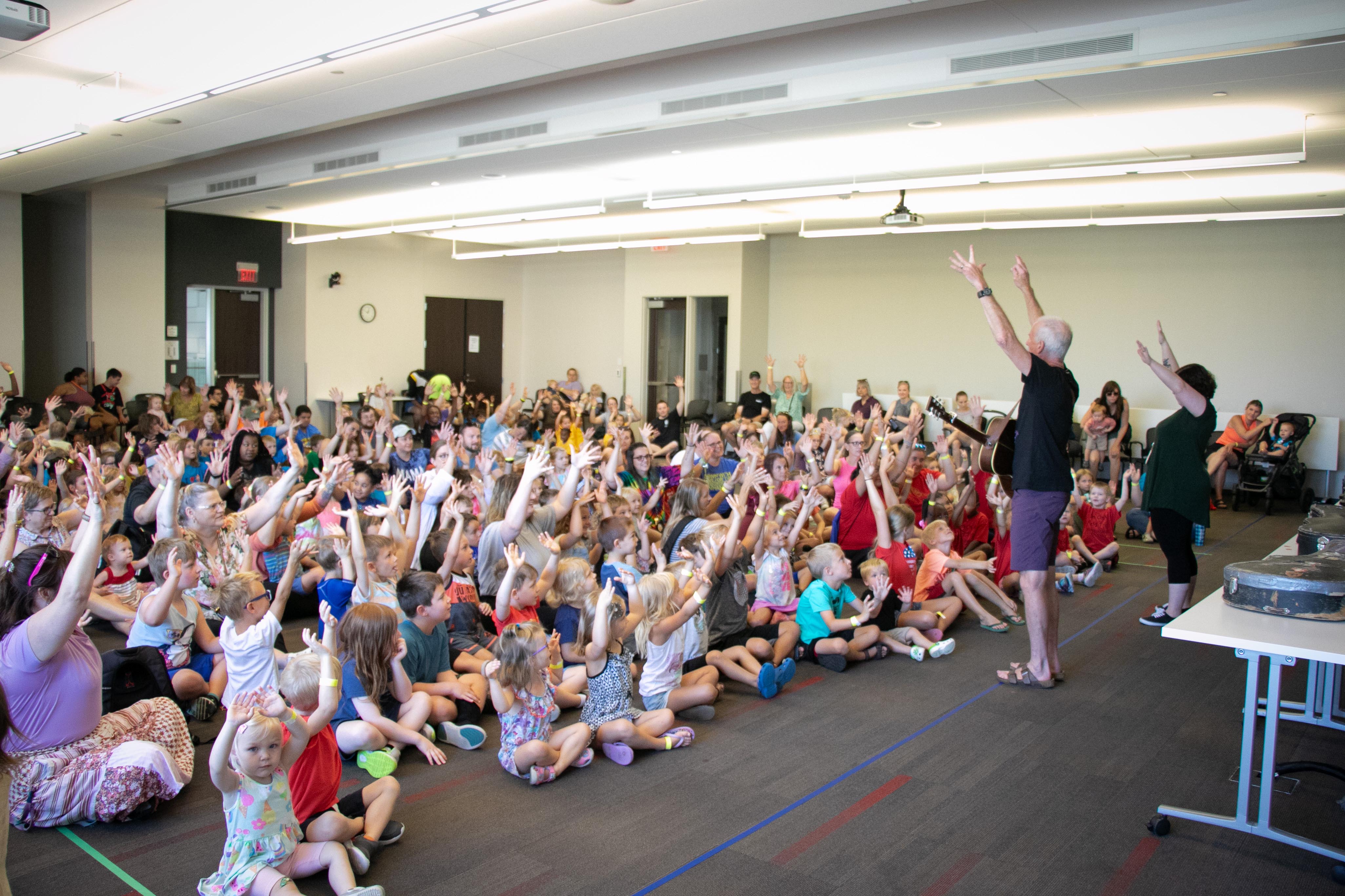 Children and Tom Pease raise their arms in the air.